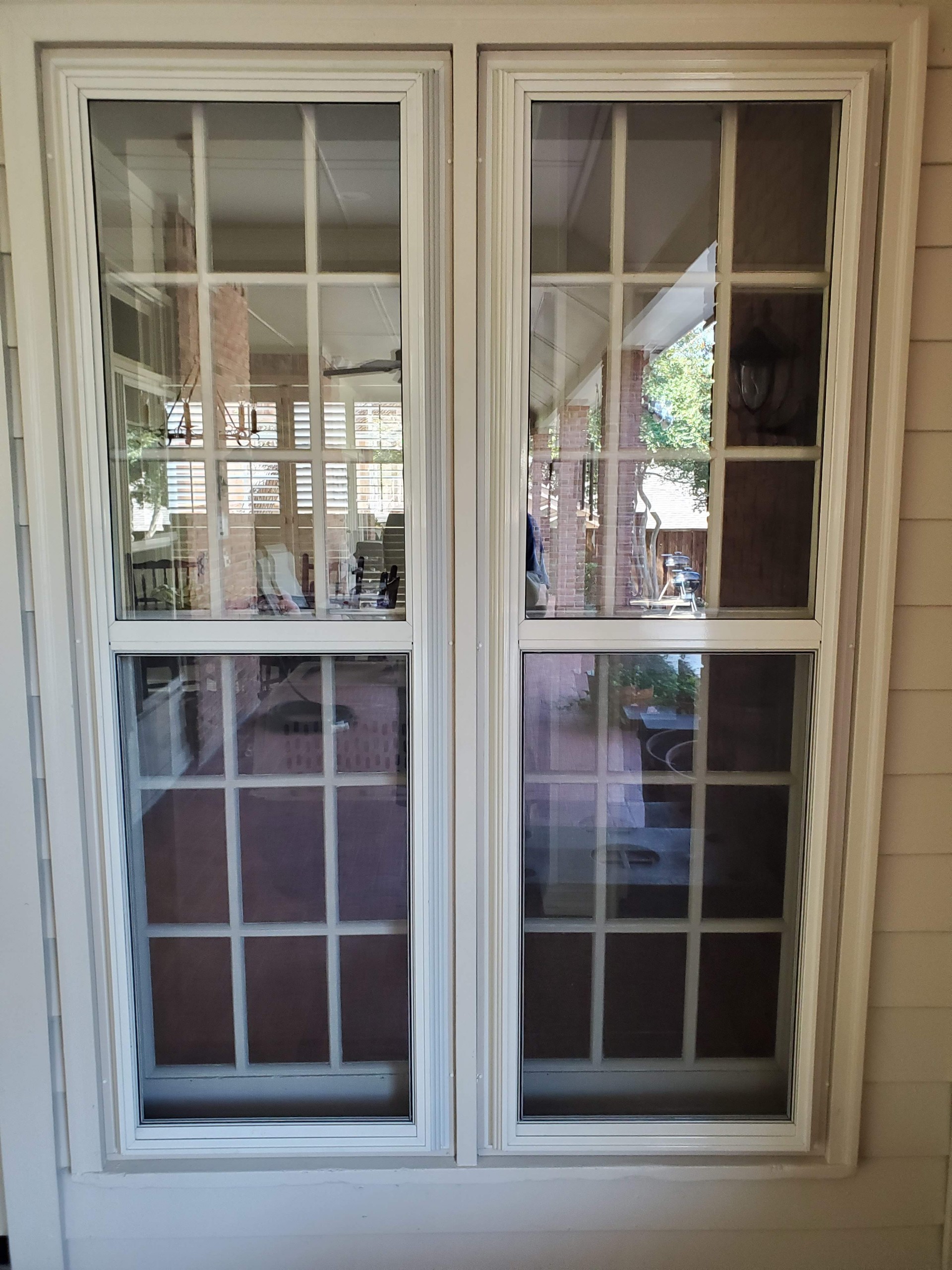 Tan storm windows installed over wood windows on brick exterior